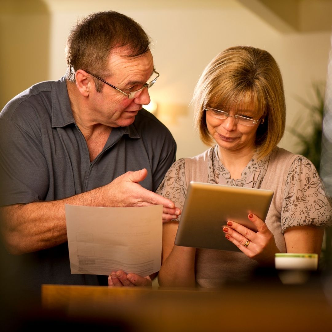 an elderly couple looking at a tablet